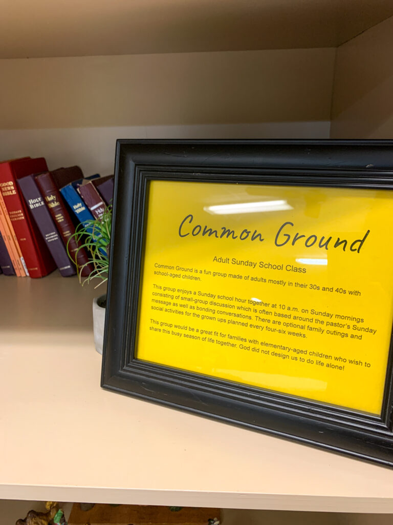 adult Sunday school names and life group name on yellow sign on Sunday school room bookshelf with Bibles 