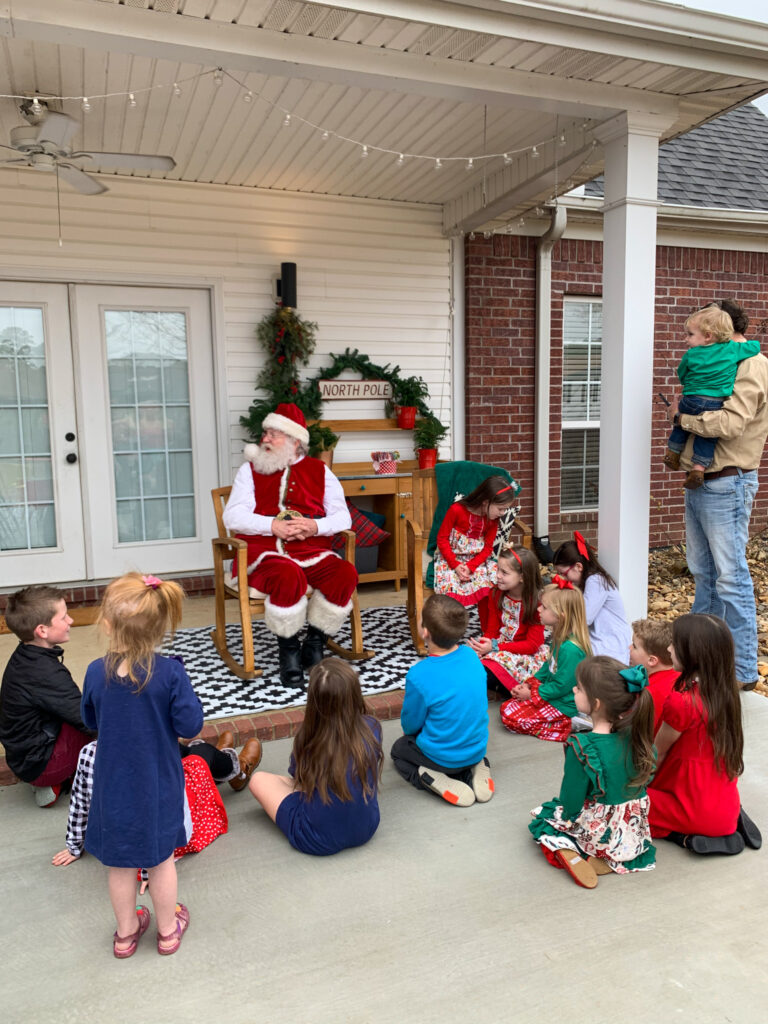 Santa visits with children on a back porch during a neighborhood Santa visit