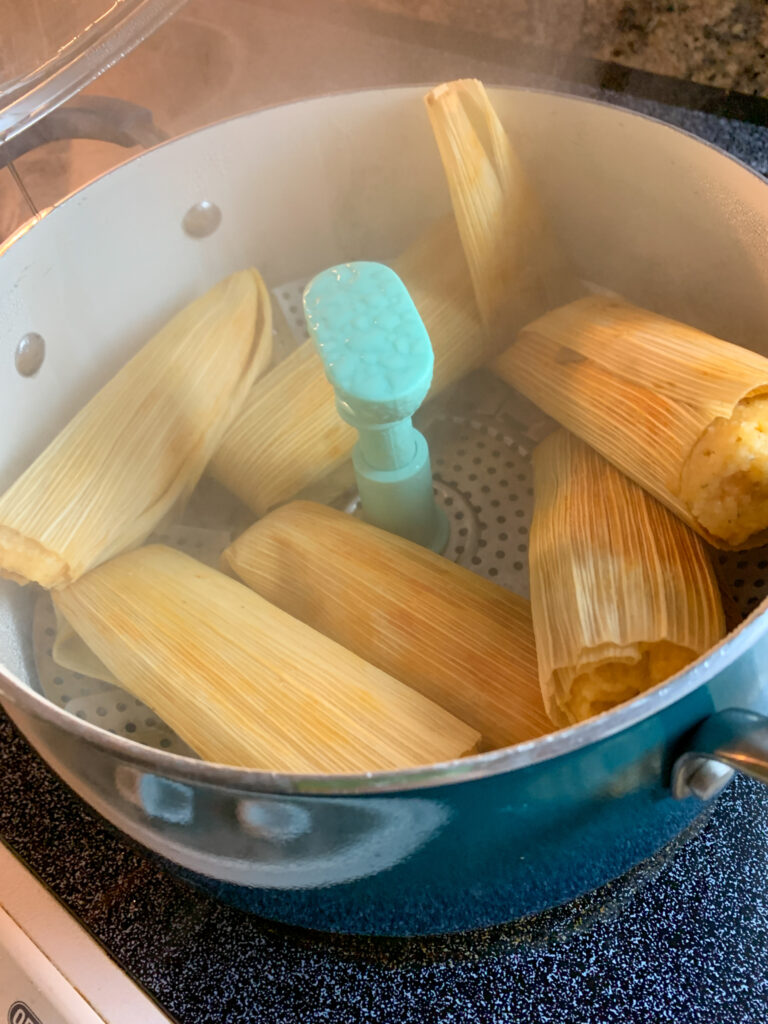 steamed tamales in an adjustable steamer basket in a stock pot on the stove