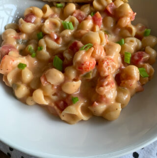white plate of crawfish mac and cheese with bread and polka dot napkin