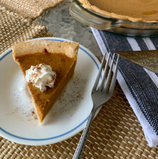 pumpkin pie with sweetened condensed milk on plate with pie plate in back