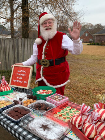 Santa waves from a cookie table at a neighborhood visit with Santa
