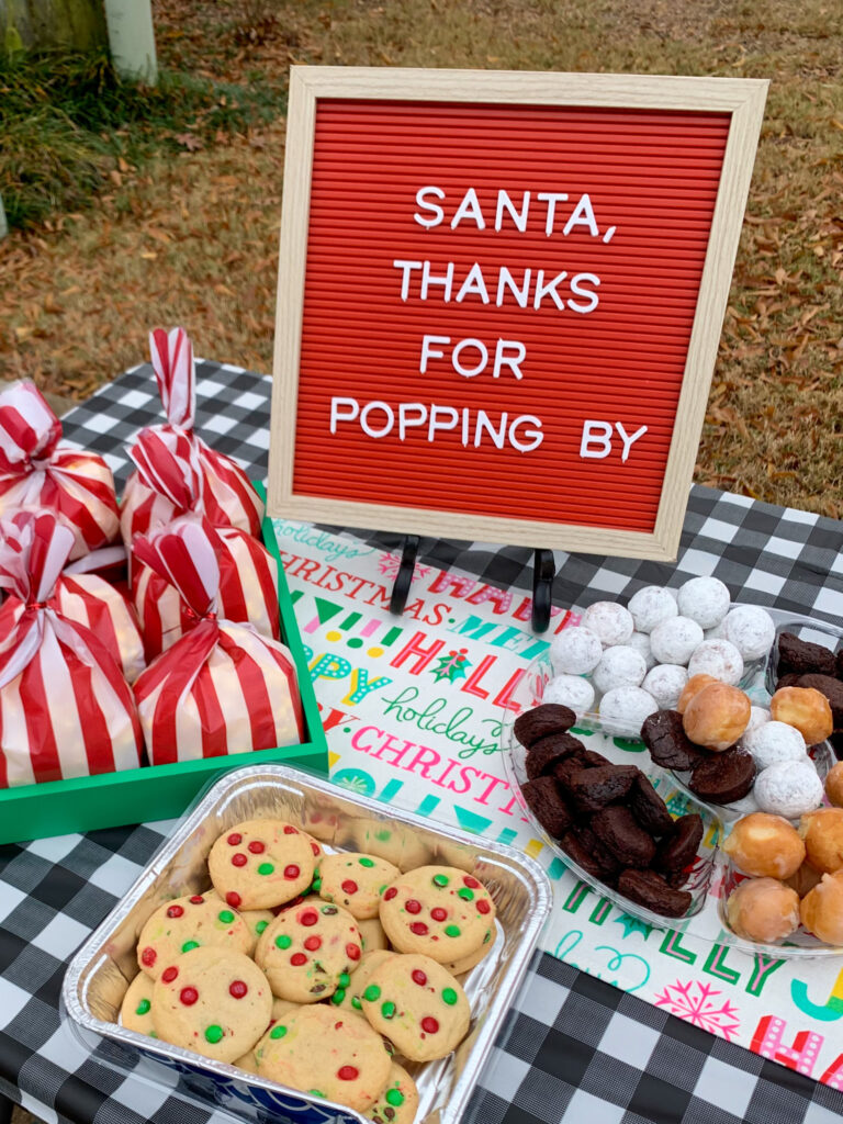 a Christmas letter board sign on the table at a holiday cookie event