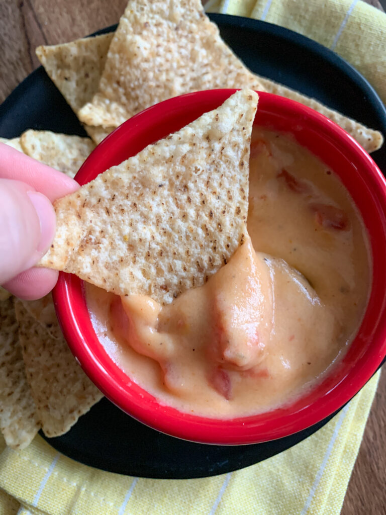 woman dips chip into spicy crawfish queso