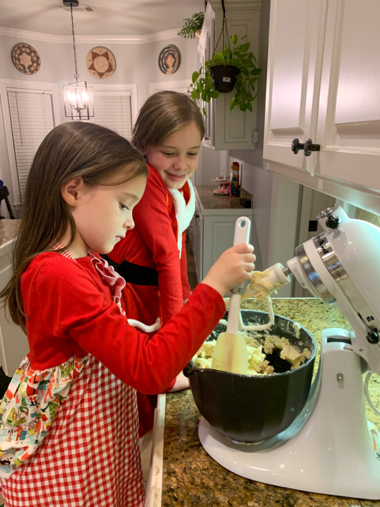 two girls mix old fashioned Christmas sugar cookies dough in Kitchenaid stand mixer