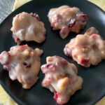 cranberry no bake cookies with pecans on black saucer on yellow cloth