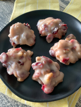 cranberry no bake cookies with pecans on black saucer on yellow cloth