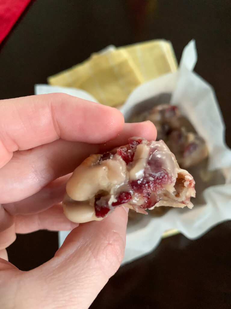 woman holds a no bake cranberry pecan praline cookie in hand