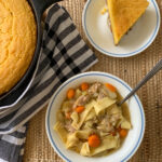 leftover turkey soup in white bowl beside cast iron skillet cornbread