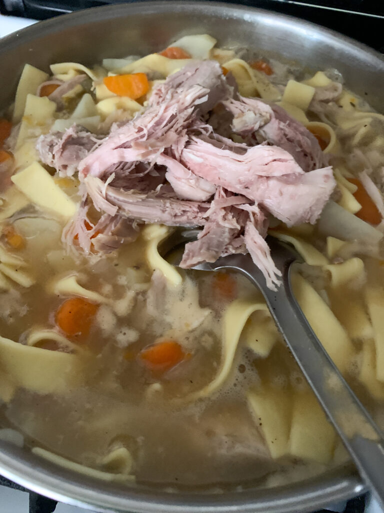 turkey being added to leftover turkey soup
