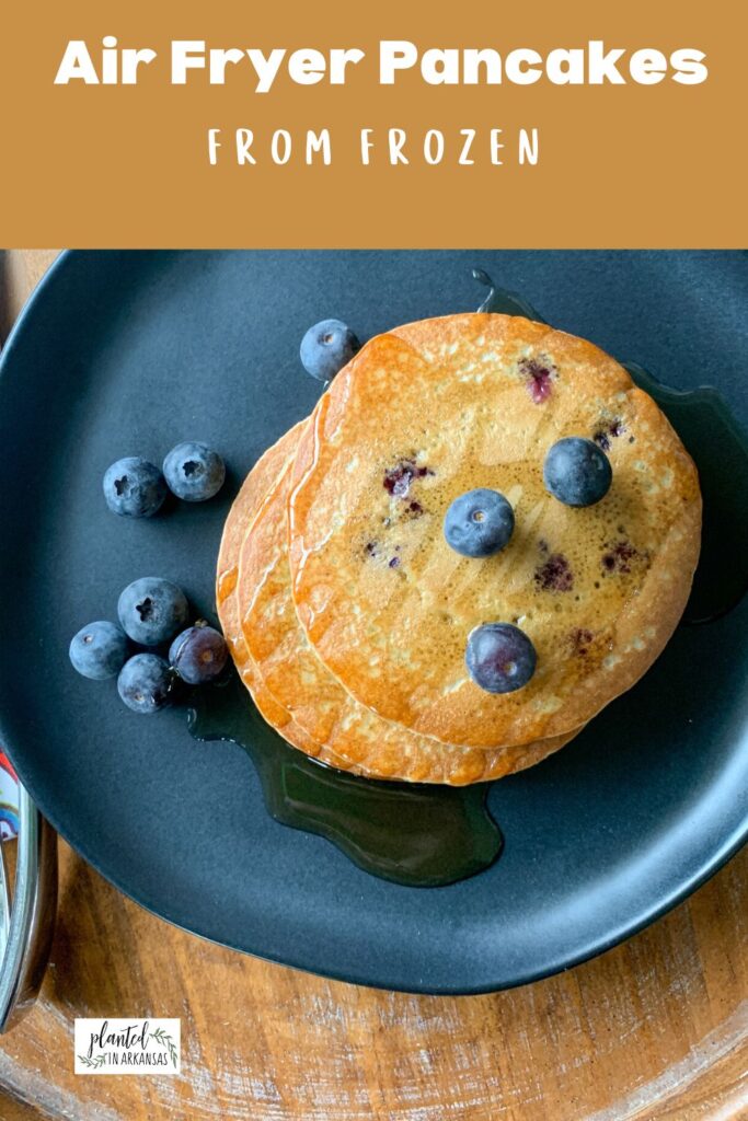 air fryer frozen pancakes with blueberries on black plate with a brown text box above