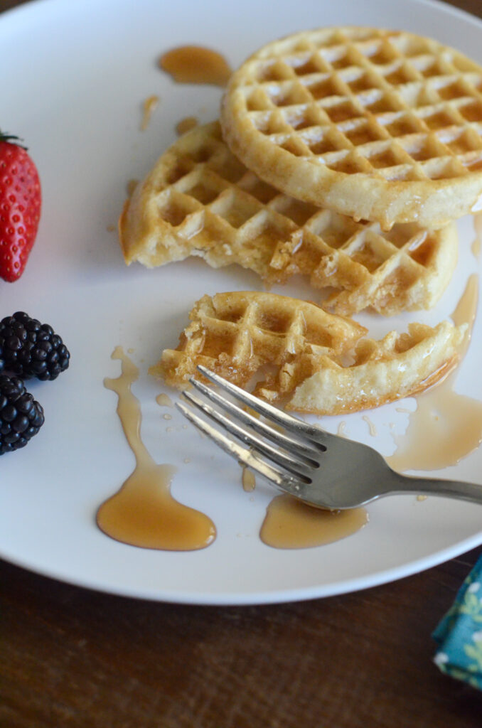 cooked Eggos on white plate with fork and fruit