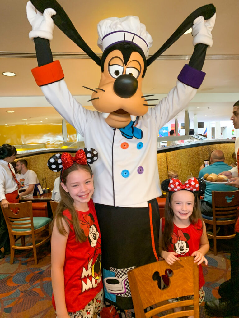 Goofy holds his ears up during a Chef Mickey breakfast with the two daughters of Arkansas lifestyle blogger, Amy