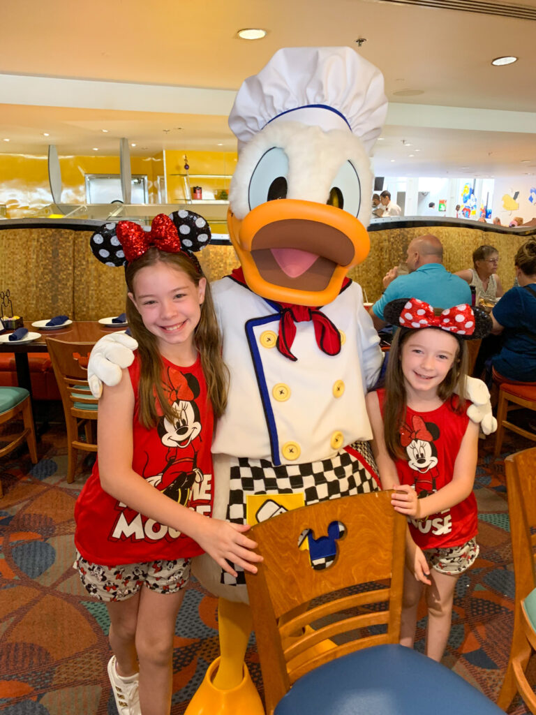 Donald Duck gives a big smile while hugging two daughters of Arkansas lifestyle blogger, Amy, of Planted in Arkansas