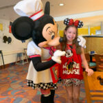 Minnie Mouse hugs girl at Chef Mickey breakfast character dining at Disney World