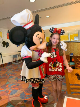 Minnie Mouse hugs girl at Chef Mickey breakfast character dining at Disney World
