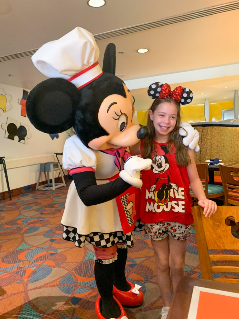Minnie Mouse hugs a young lady at a Disney World character dining experience