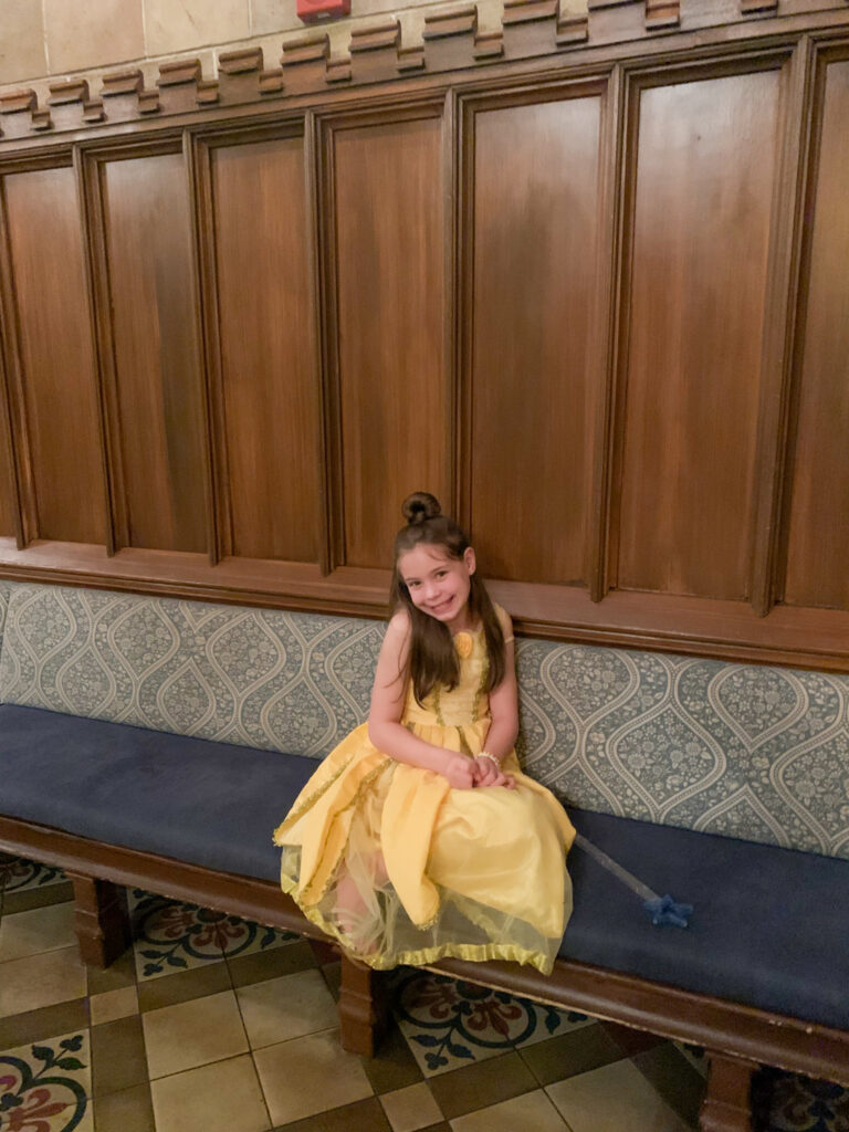 little girl sits on benches in Cinderella's Royal Castle at Magic Kingdom