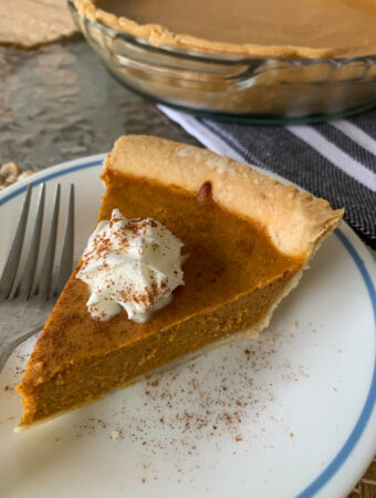 slice of creamy pumpkin pie with condensed milk on white and blue saucer