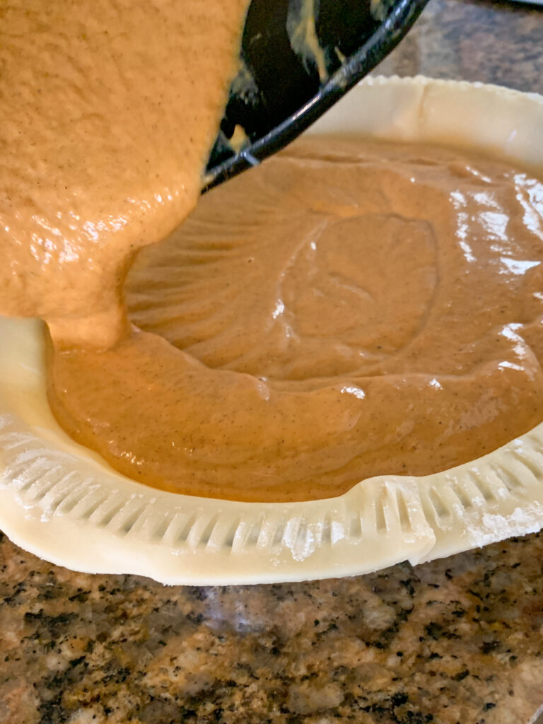 creamy pumpkin pie with condensed milk filling going into pie shell