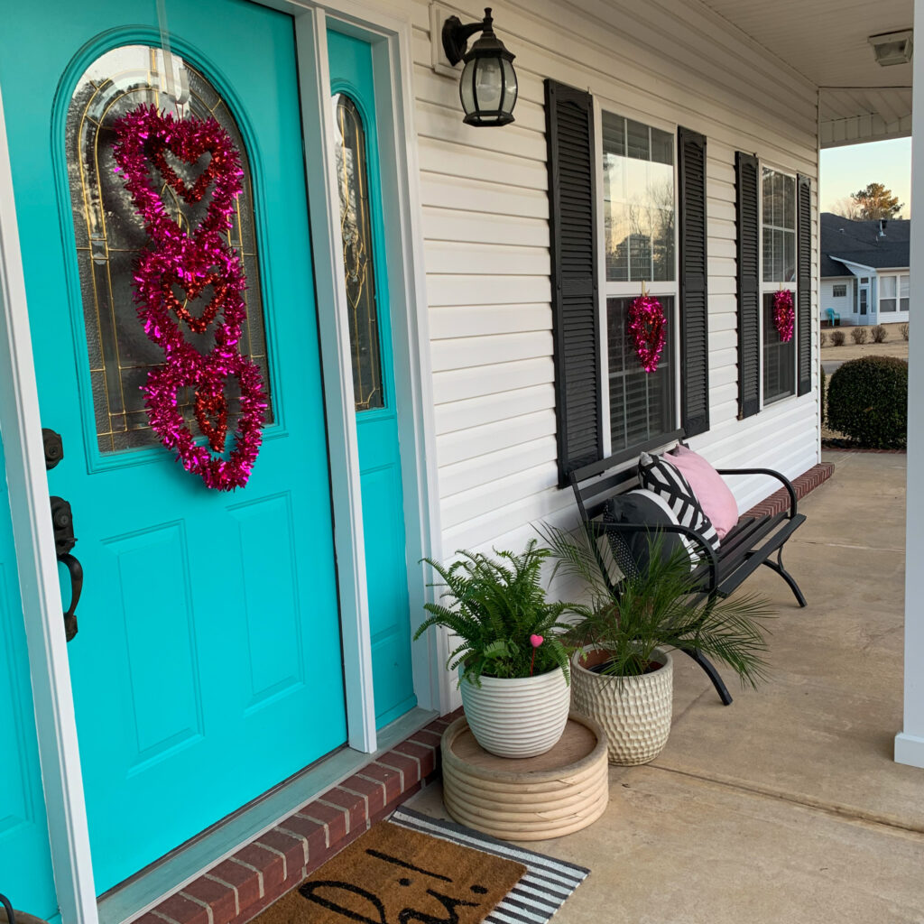 Valentine's Day porch decor with door mat, heart tinsels and flower pots