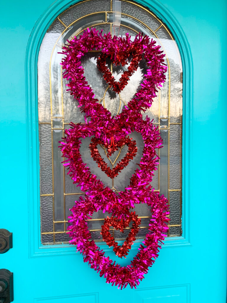 pink tinsel hearts for Valentine's Day door decor on turquoise door for simple Valentine's Day porch decor