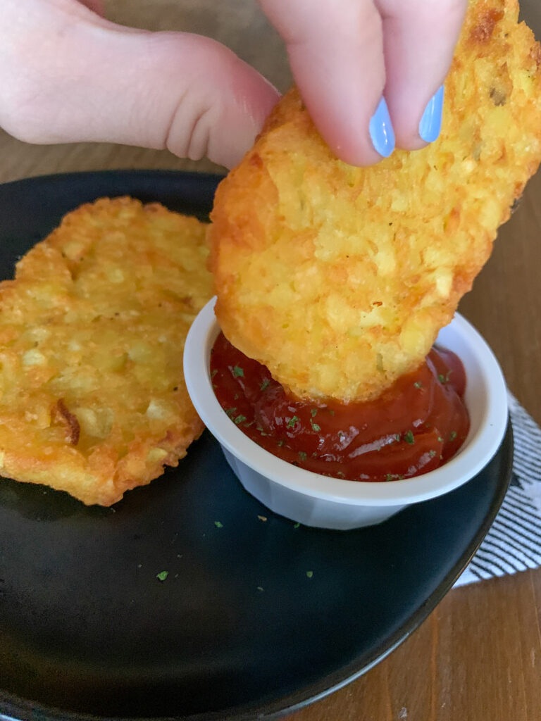 woman with blue nails dips potatoes into ketchup