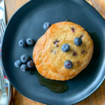 frozen pancakes in air fryer cooked and waiting on black plate with blueberries