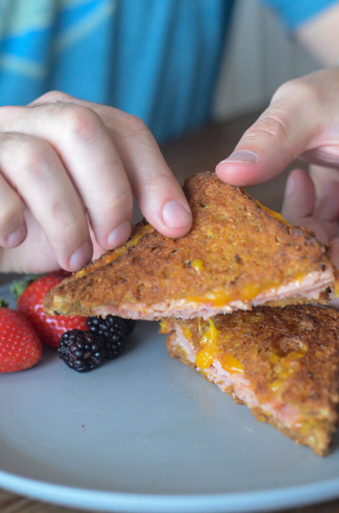 man picks of cheesy grilled air fryer ham and cheese sandwich