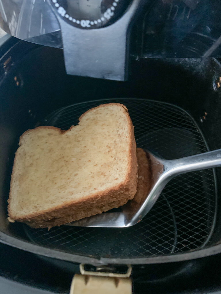 a spatula flips an air fryer peanut butter and jelly in the air fryer basket