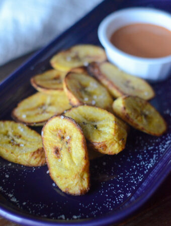 air fryer plantains with cup of sriracha mayo in white cup - on top of purple plate