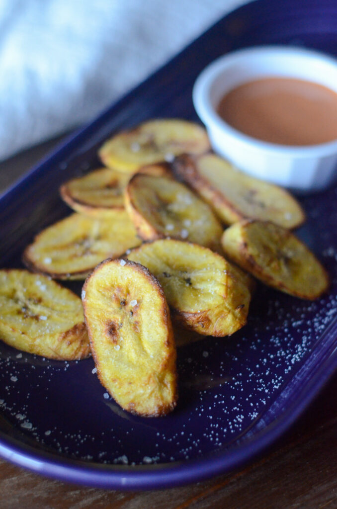 air fryer sweet plantains on purple tray with sriracha mayonnaise sauce in white bowl