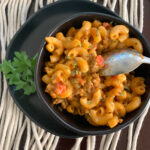 black bowl with cheesy beef and macaroni skillet meal with a spoon