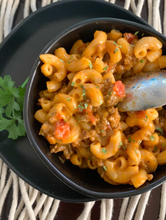 black bowl with cheesy beef and macaroni skillet meal with a spoon