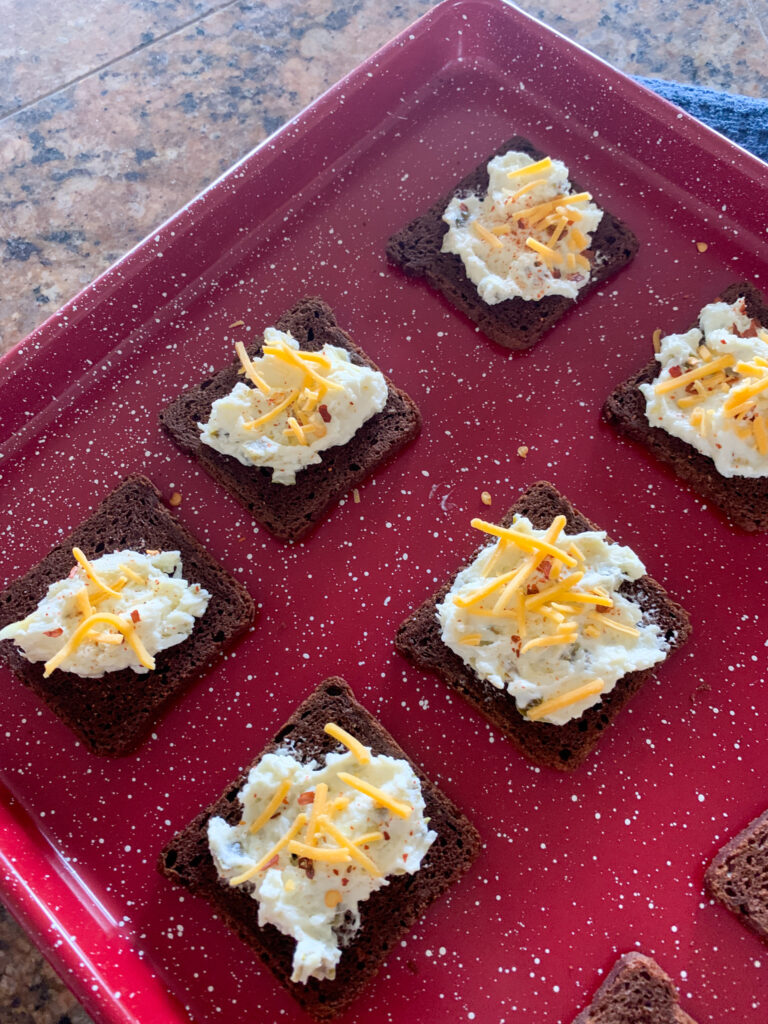 assembled jalapeno artichoke dip on rye bread appetizer before tray goes in oven