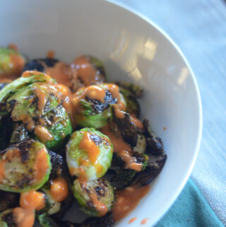 white bowl of skillet Brussels sprouts with honey sriracha