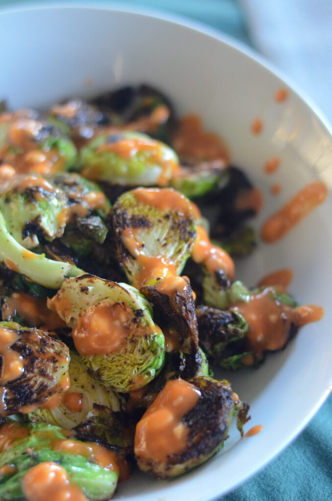pan fried Brussels sprouts with honey sriracha sauce in white bowl 