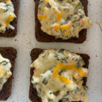 spinach dip on rye bread appetizers on white cookie sheet