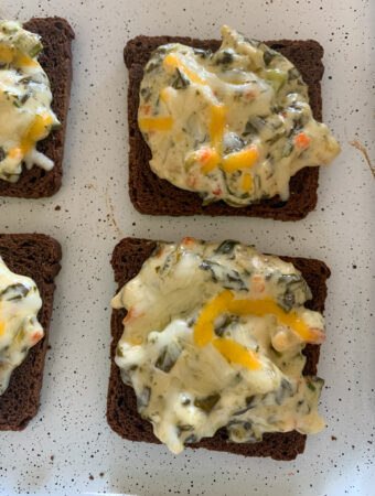 spinach dip on rye bread appetizers on white cookie sheet