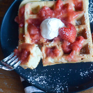 strawberry waffles with strawberry sauce on black plate