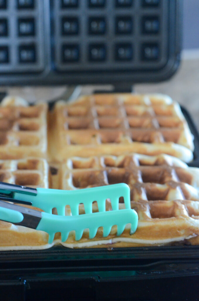 thick fluffy waffles in Cuisineart waffle maker with clawed tongs