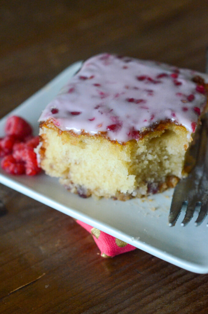raspberry white chocolate cake with raspberry cake glaze on white saucer with fork