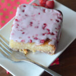 white chocolate and raspberry cake with on white saucer with polka dot napkin