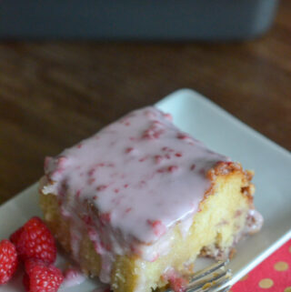 slice of white chocolate and raspberry cake on white plate with pink napkin