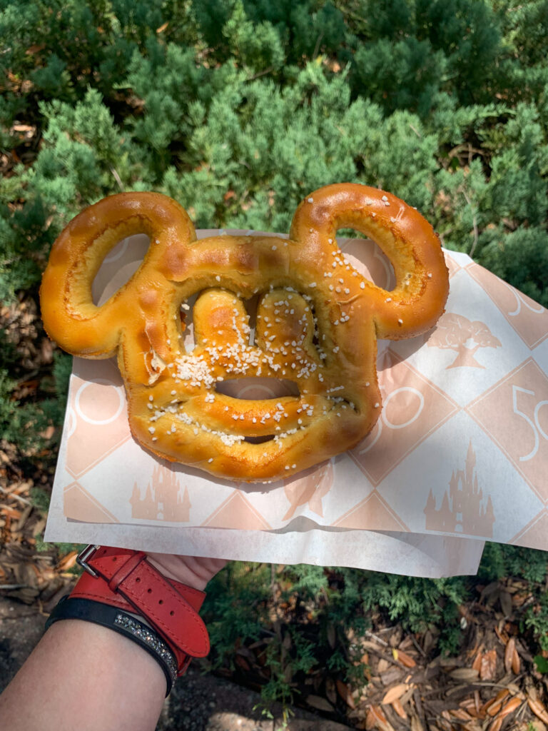 woman holds Mickey Mouse pretzel in hand at Hollywood Studios - visited as part of a family Disney World itinerary