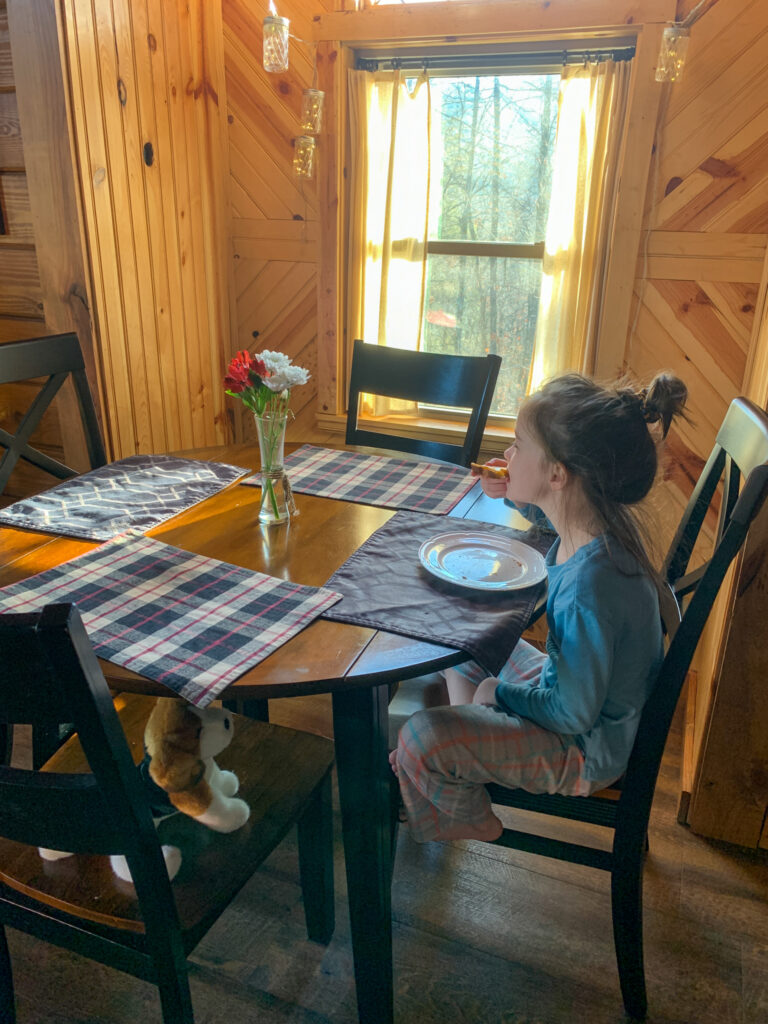 little girl eats at a drop leaf table in a luxury cabin in Arkansas