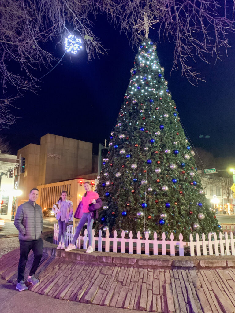 dad and children stand in front of large Christmas tree in downtown Hot Springs
