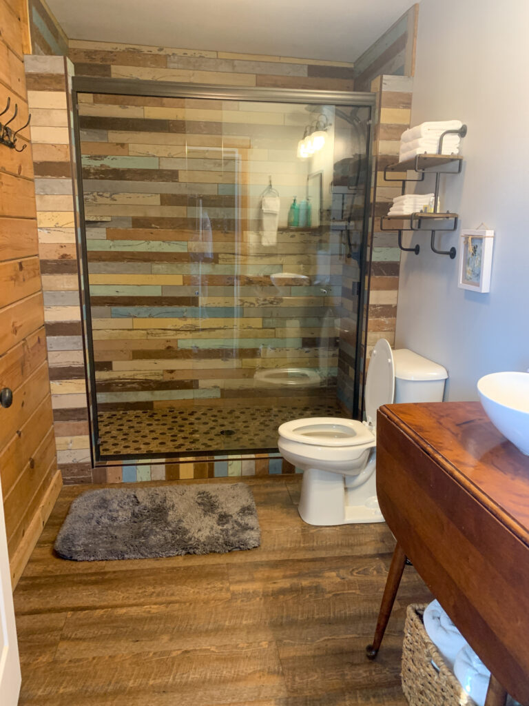 a rustic bathroom with plank wall tile in the shower