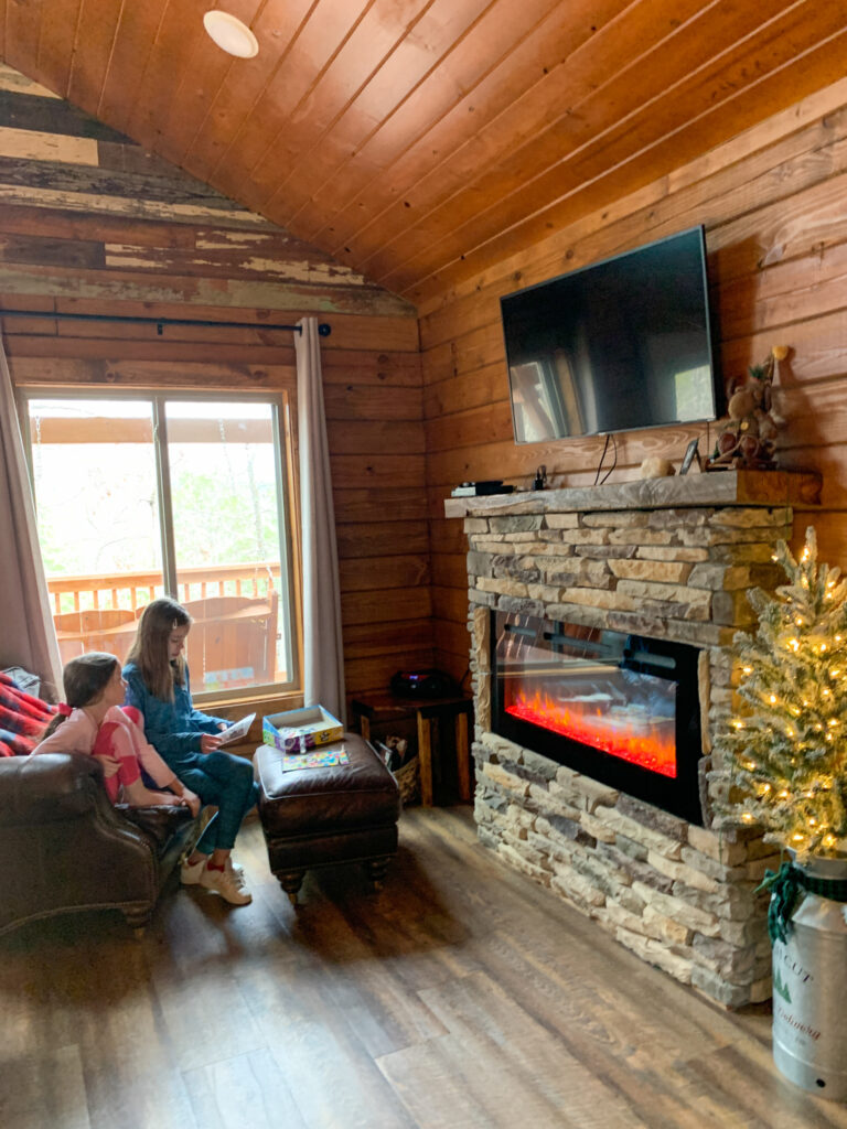 children play a board game in the living room area of luxury Hot Springs treehouse cabin at Starlight Haven