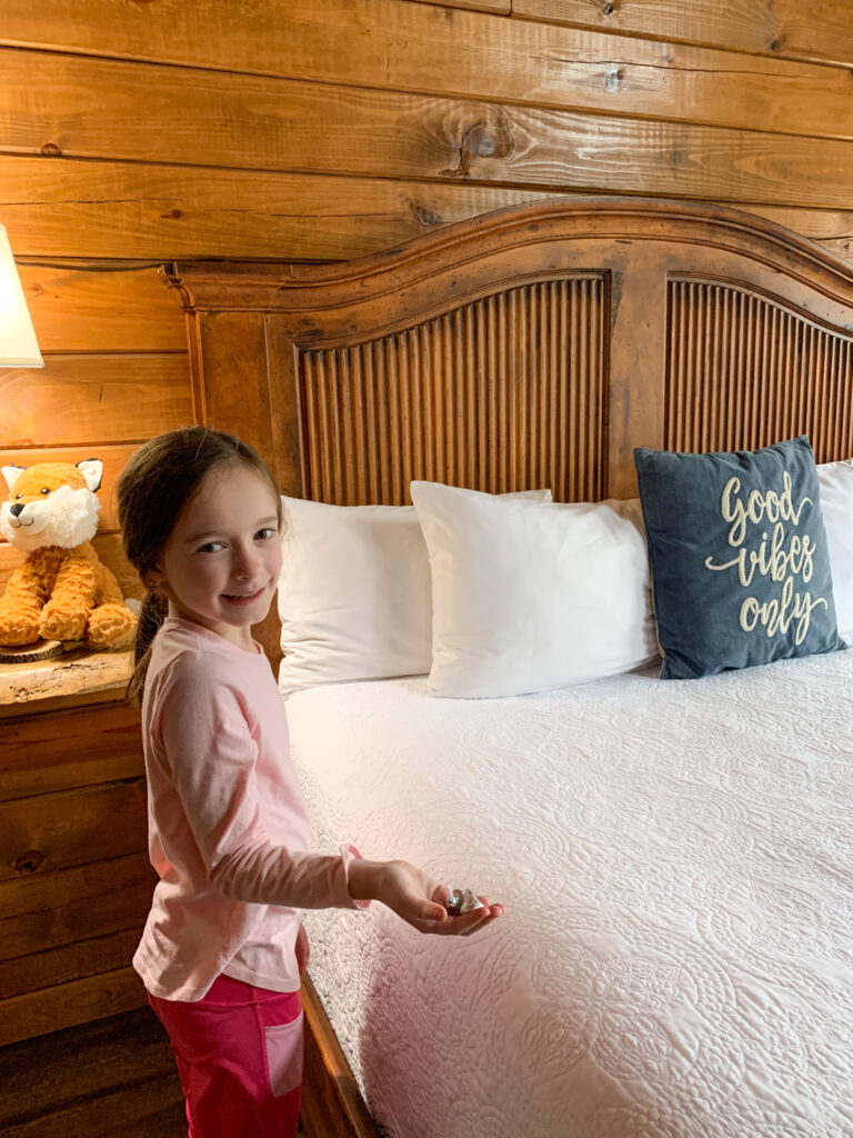little girl holds candy left on bed at vacation rental 